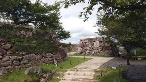 Ruins-of-Takeda-Castle-in-Japan,-lush-pathway-between-ancient-foundations-of-fortress