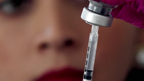 female doctor or nurse fills a syringe from a vial of medication - close up