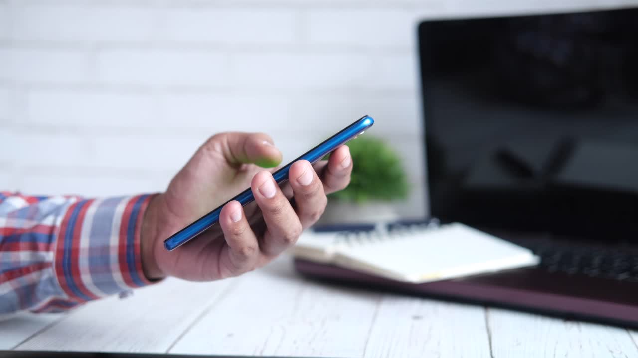 persona que usa un teléfono inteligente en un escritorio con una computadora portátil