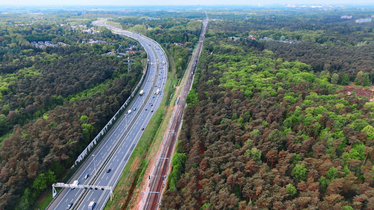 Highway adjacent to dense forest region. Aerial view of a busy highway beside a lush forest, showcasing the coexistence of nature and infrastructure