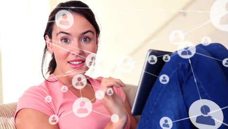 Animation-of-network-of-connections-with-icons-over-caucasian-woman-using-tablet