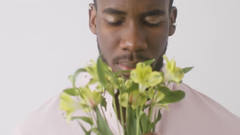 young man with make up smelling flowers