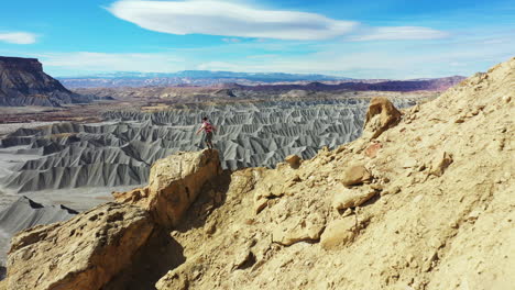 man standing on top of the rock above desert landscape of utah