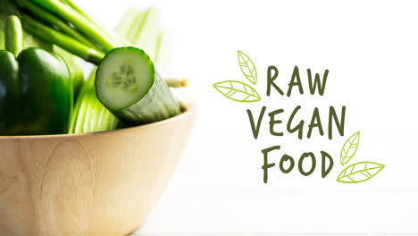 animación de texto vegano crudo en verde sobre un tazón de ensalada de verduras orgánicas frescas en tablas de madera