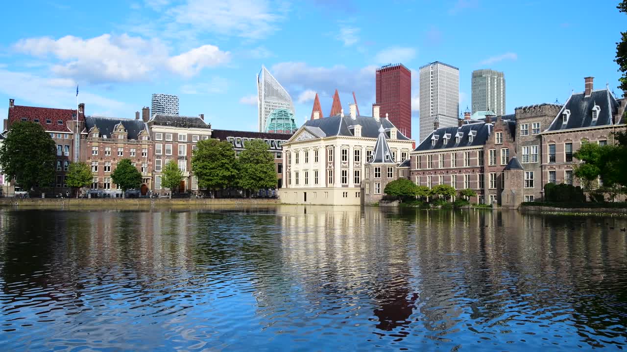 Refleksion i Hofvijver, den hollandske parlamentsbygning med Den Haags bybillede i baggrunden, og vinden, der blæser på søoverfladen og skaber bølger under en smuk solrig forårsdag i Holland.