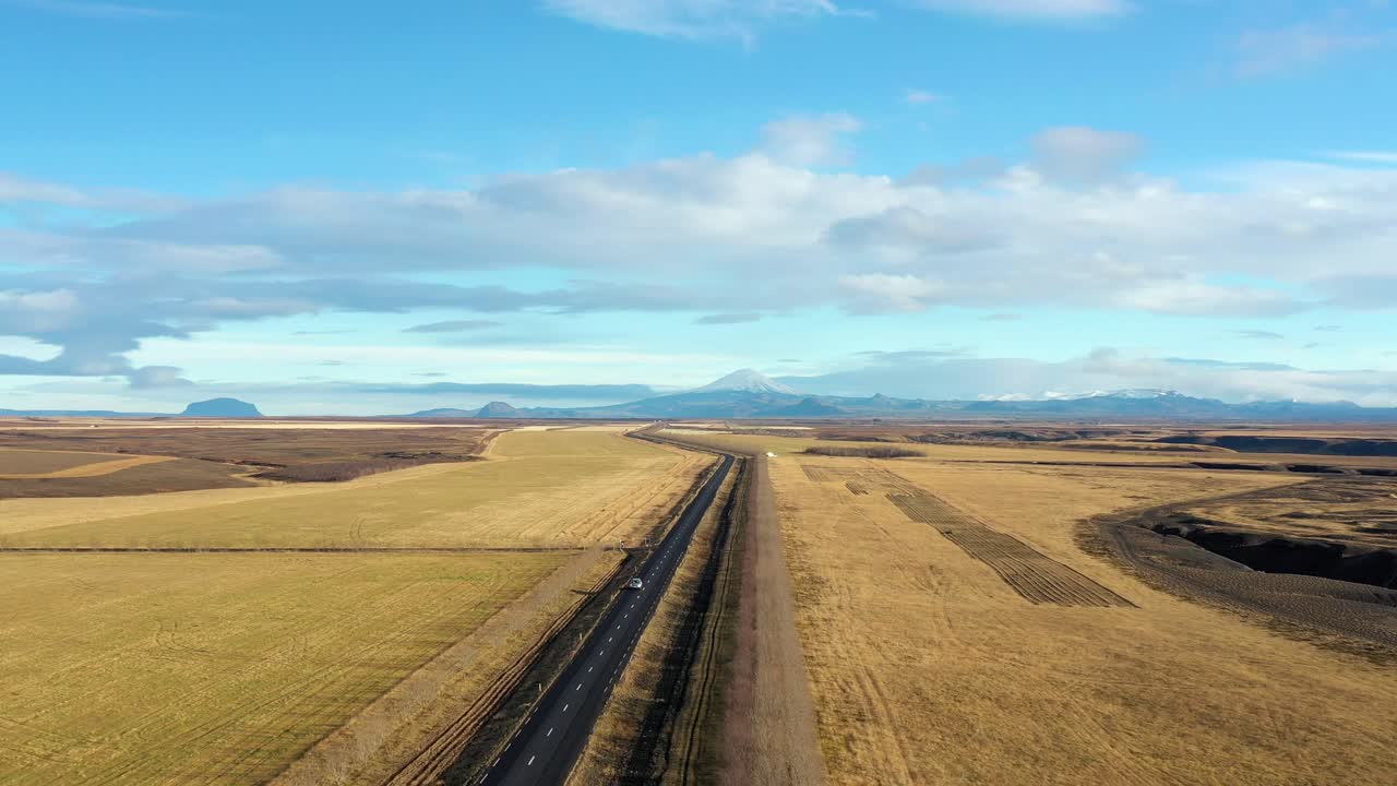 Luftfoto af et køretøj, der kører på en tosporet motorvej på Island med en fantastisk naturbaggrund