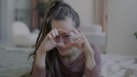 woman with dreadlocks making heart shape with hands