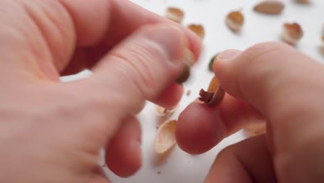 Man peeling pistachios with his hands. Close up
