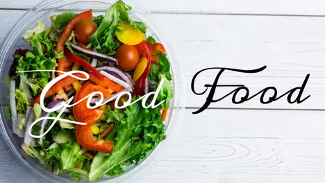 animation of good food text in black and white, over bowl of fresh salad on white wooden boards