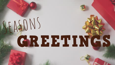 animation of seasons greetings with gift boxes, baubles, leaves over white table