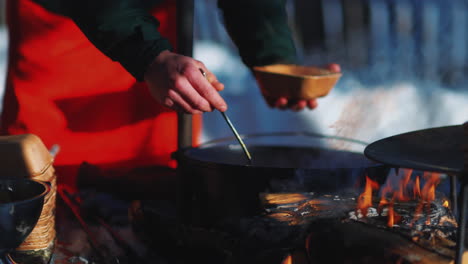 man serving steaming bowl of moose soup outside for seasonal swedish meal