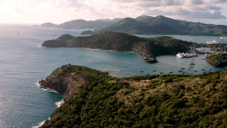 toma aérea de la puesta de sol en puerto inglés en antigua, caribe con vistas de yates, veleros, puerto deportivo, bahía y acantilados