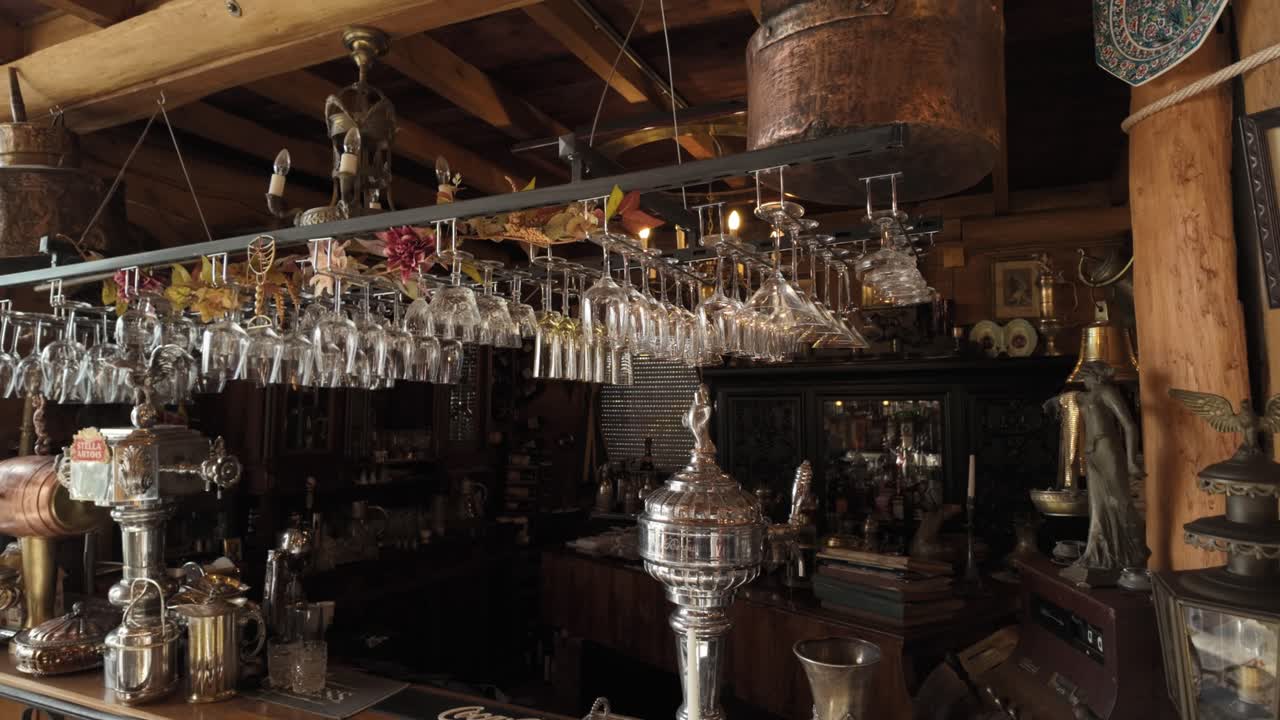 Warm shot of rustic bar filled with hanging glasses and antique objects