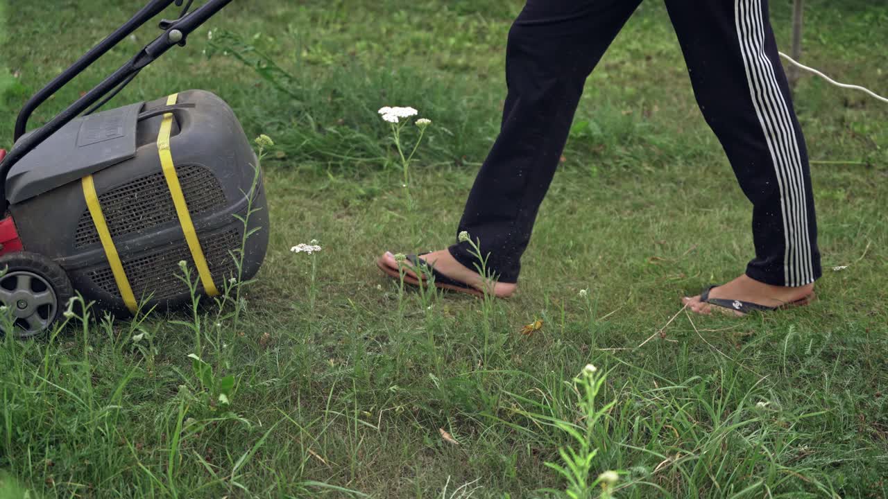 lawn mower at work on a green meadow at summertime