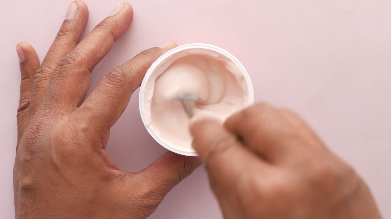 человек ест йогурт с ложкой