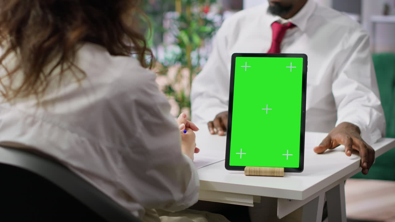 el entrevistador y el candidato se reúnen para una entrevista junto a la pantalla verde