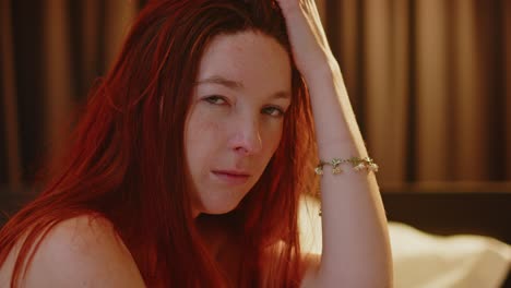 Portrait-of-A-lovely-young-woman-with-long-read-hair-sitting-in-her-bedroom