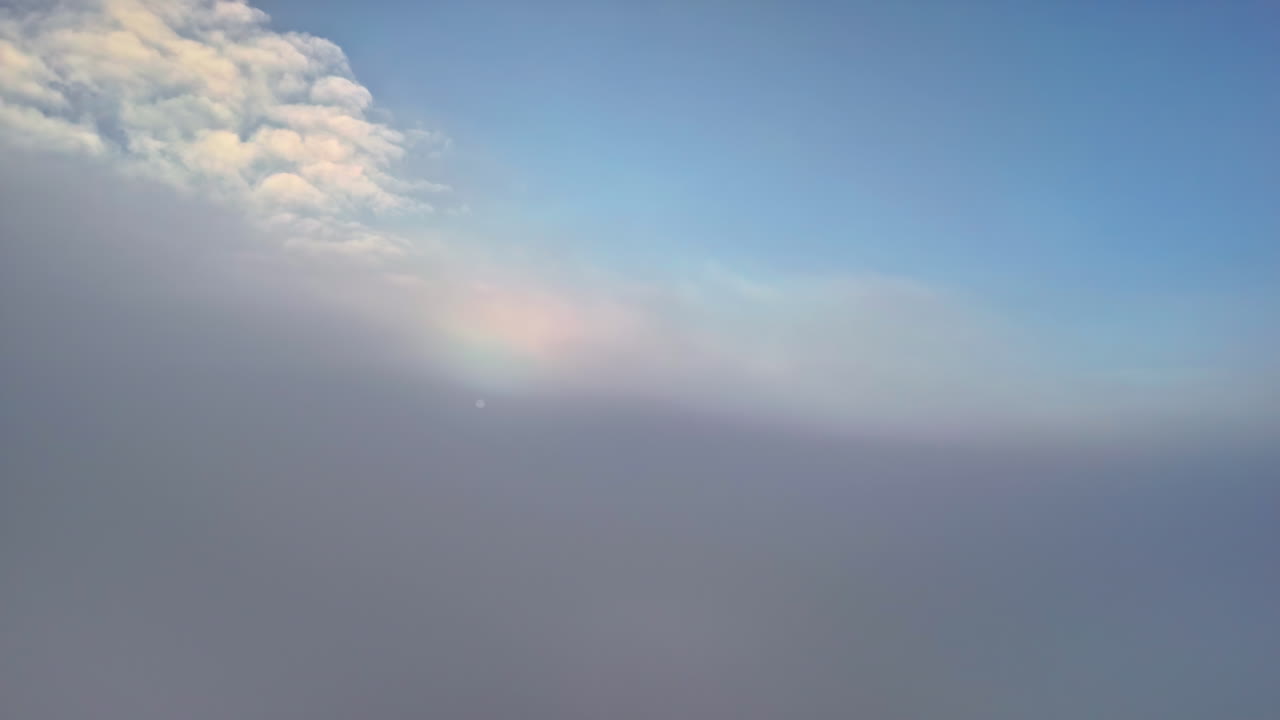 Drone advances above a cloud layer and enters dense fog, causing the faint sun to fade almost completely from view