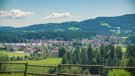 Vista-Panorámica-Izquierda-A-Través-De-La-Campiña-Boscosa-Con-La-Ciudad-En-La-Distancia-En-Kotlje,-Eslovenia