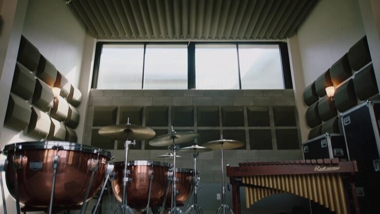 Lenta inclinazione della telecamera verso l'alto che rivela un set di percussioni in una sala prove, mostrando timpani di rame.