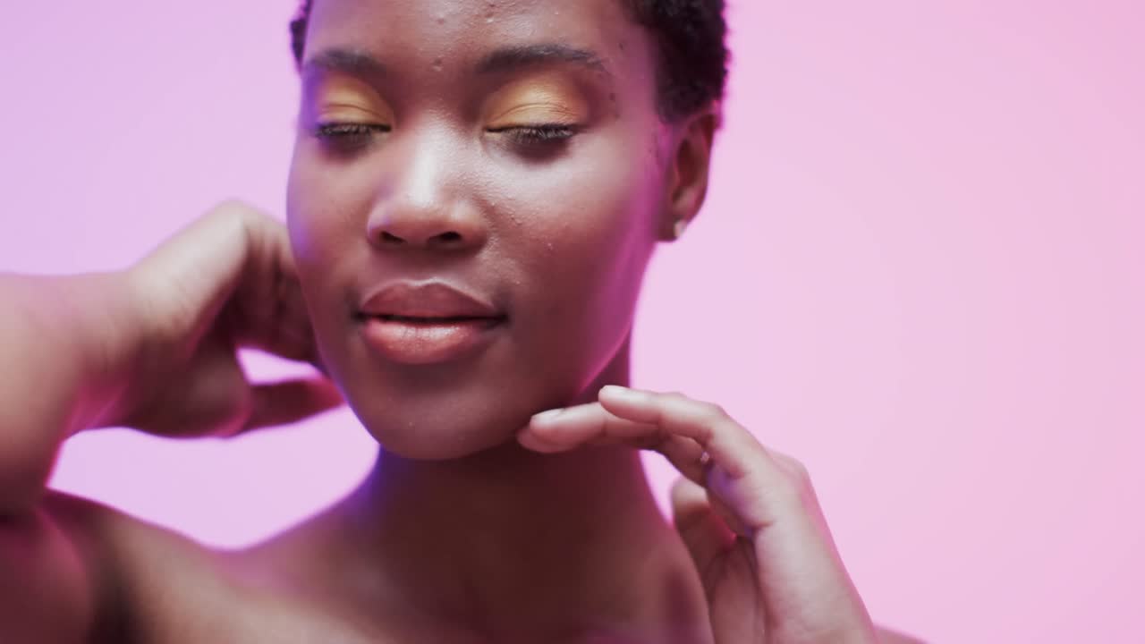 Femme afro-américaine aux cheveux courts foncés sous une lumière bleue et rose, au ralenti