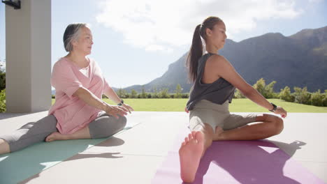 practicing yoga, women stretching on mats outdoors with mountain view