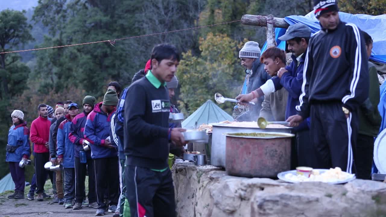 Himalayan mountaineers at their tent colony having lunch.getting lunch standing in queue with discipline in upper Himalayas, Uttarakhand India.