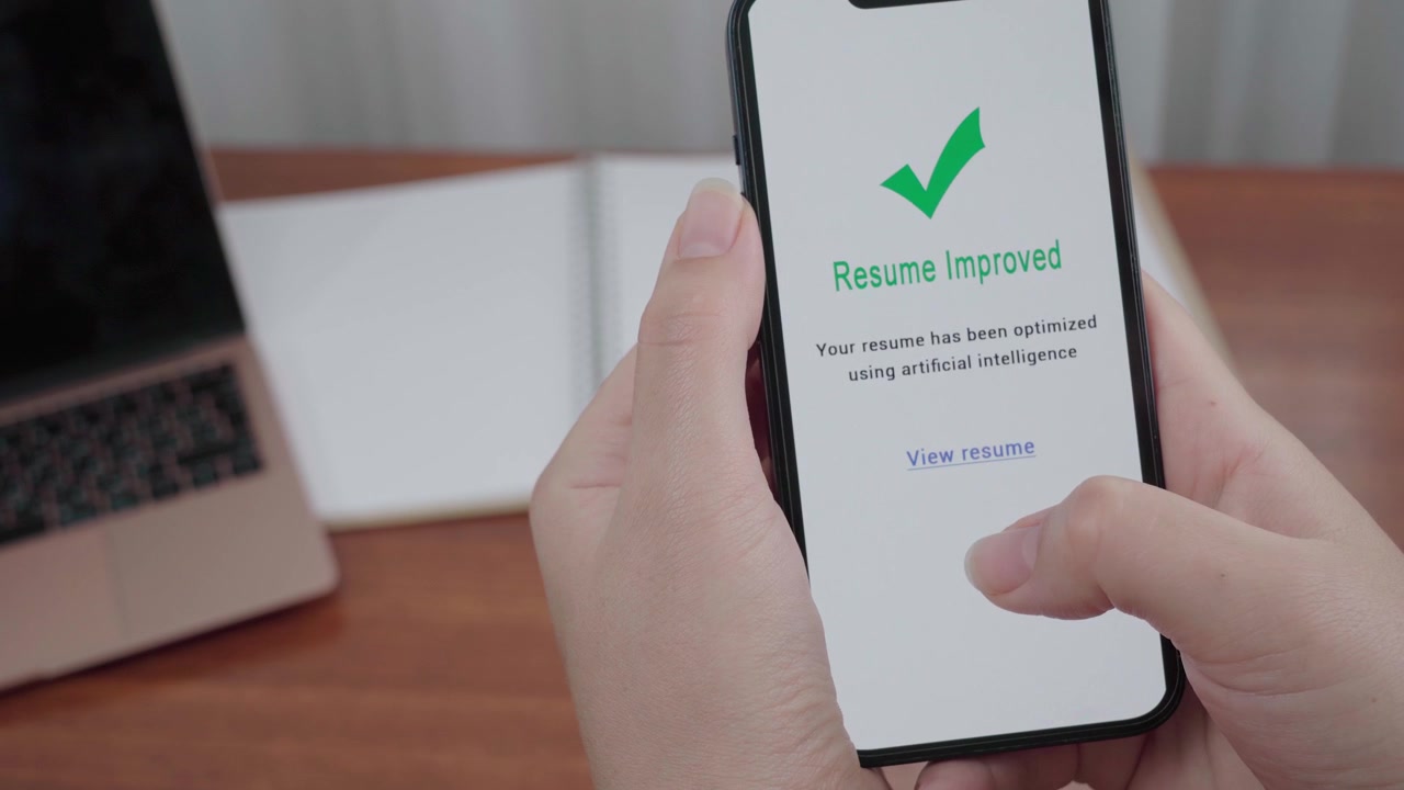 Una persona tiene uno smartphone che mostra una schermata di un'app per curriculum con IA, con una spunta verde e un avviso 'Curriculum Migliorato'