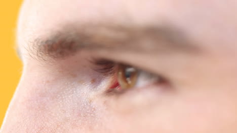 close up of eye of caucasian man against yellow background