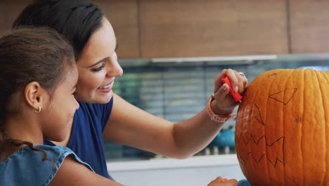 madre e hija tallando linterna de halloween de calabaza en casa