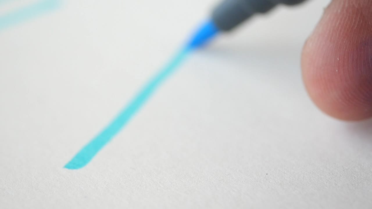 un primer plano de un marcador azul escribiendo en un pedazo de papel.