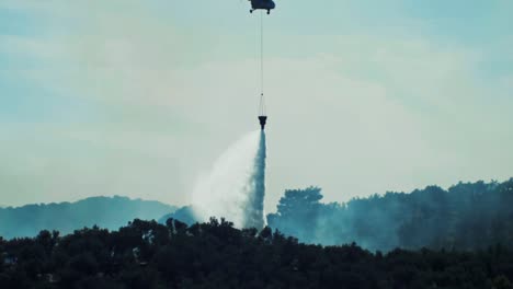 helicopter dropping water putting out forest fire