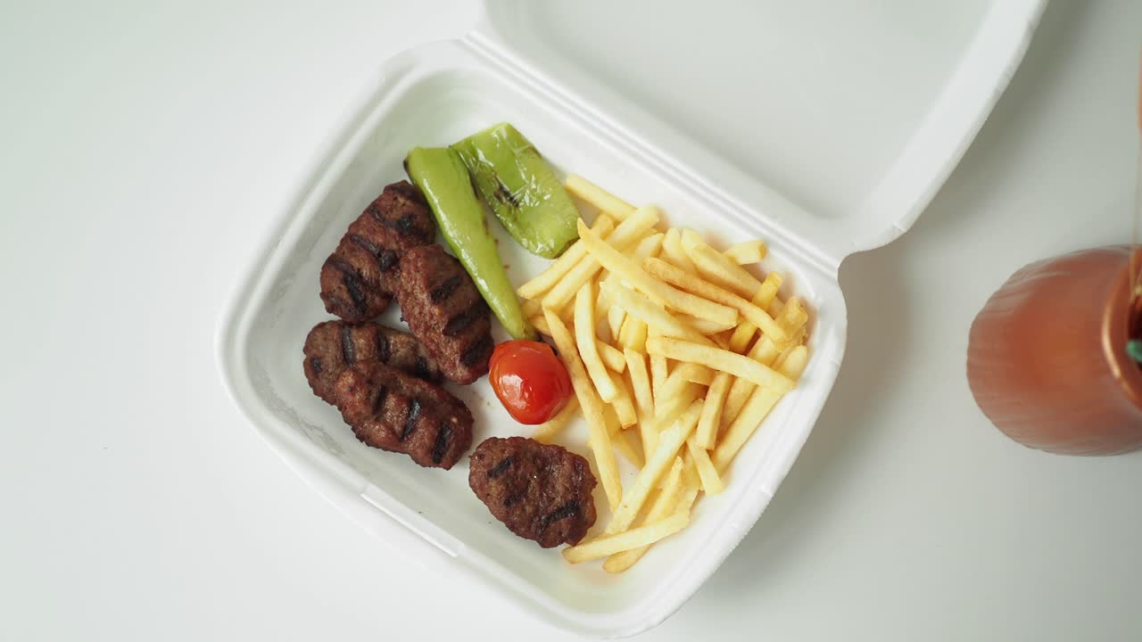 kofta y papas fritas en una caja de comida para llevar