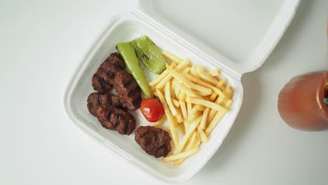 kofta and fries meal in a takeaway box