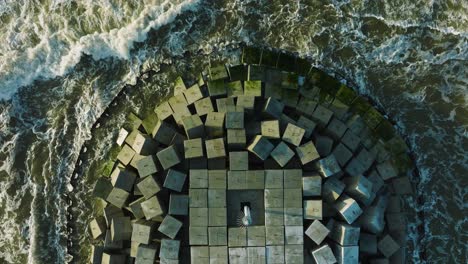 Aerial-establishing-view-of-protective-pier-with-concrete-blocks-and-rocks-at-Baltic-sea-coastline-at-Liepaja,-Latvia,-strengthening-beach-against-coastal-erosion,-ascending-birdseye-drone-shot
