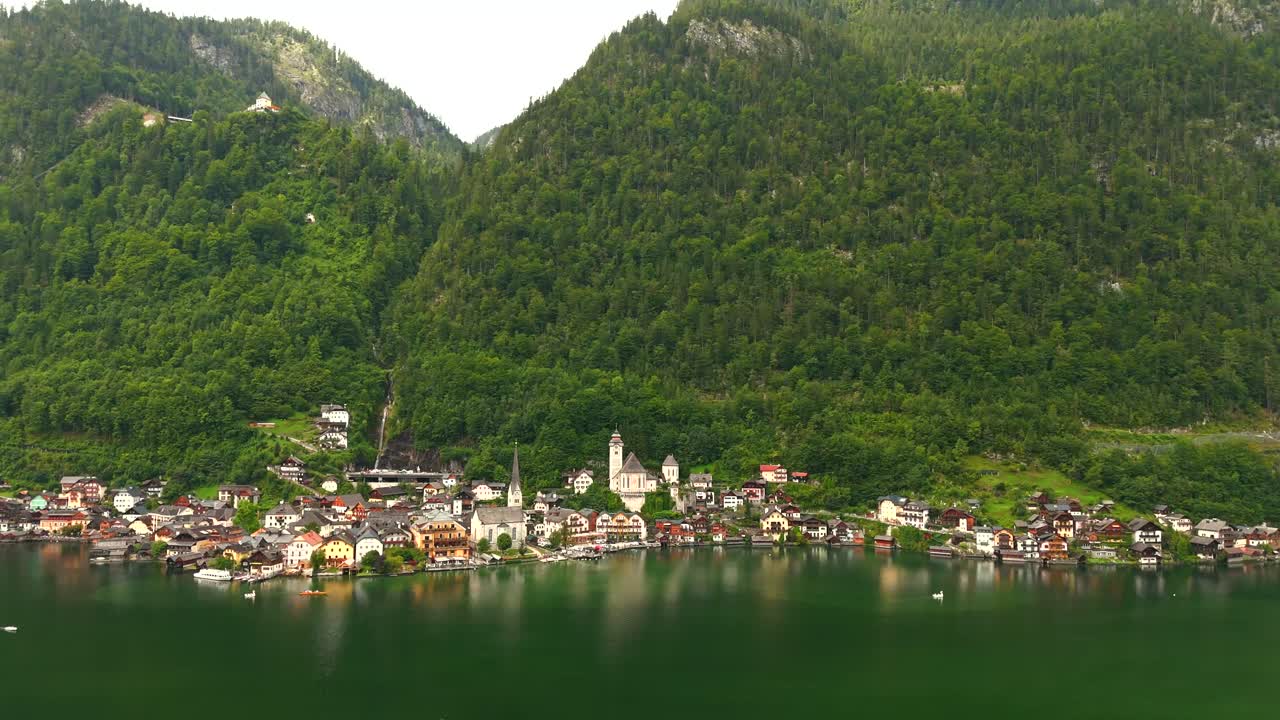 Aerial view of Hallstatt, Austria, captured by drone, showcasing its picturesque lakeside homes, majestic mountains, and the unique charm of this enchanting alpine village.
