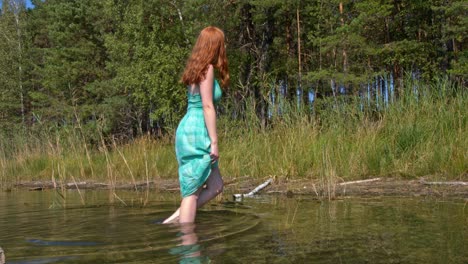 mujer pelirroja caminando en el agua en el lago