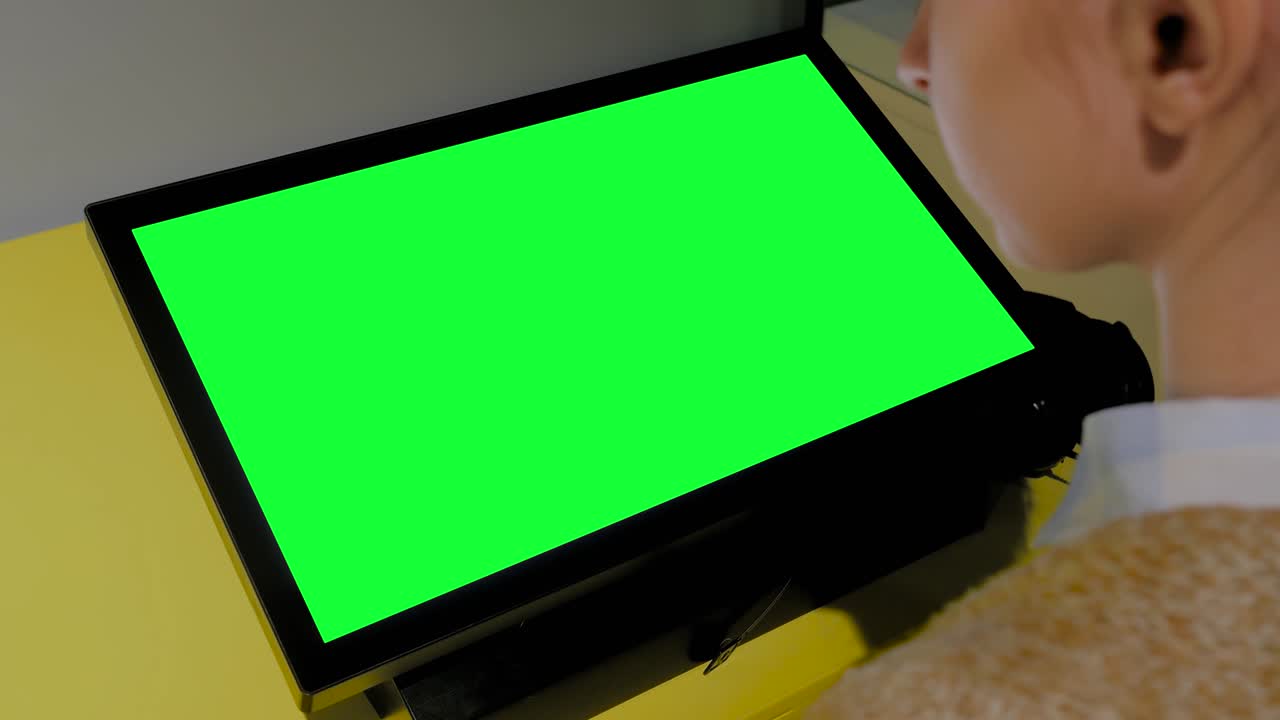 mujer mirando un quiosco de exhibición verde en blanco en una exposición - concepto de pantalla verde