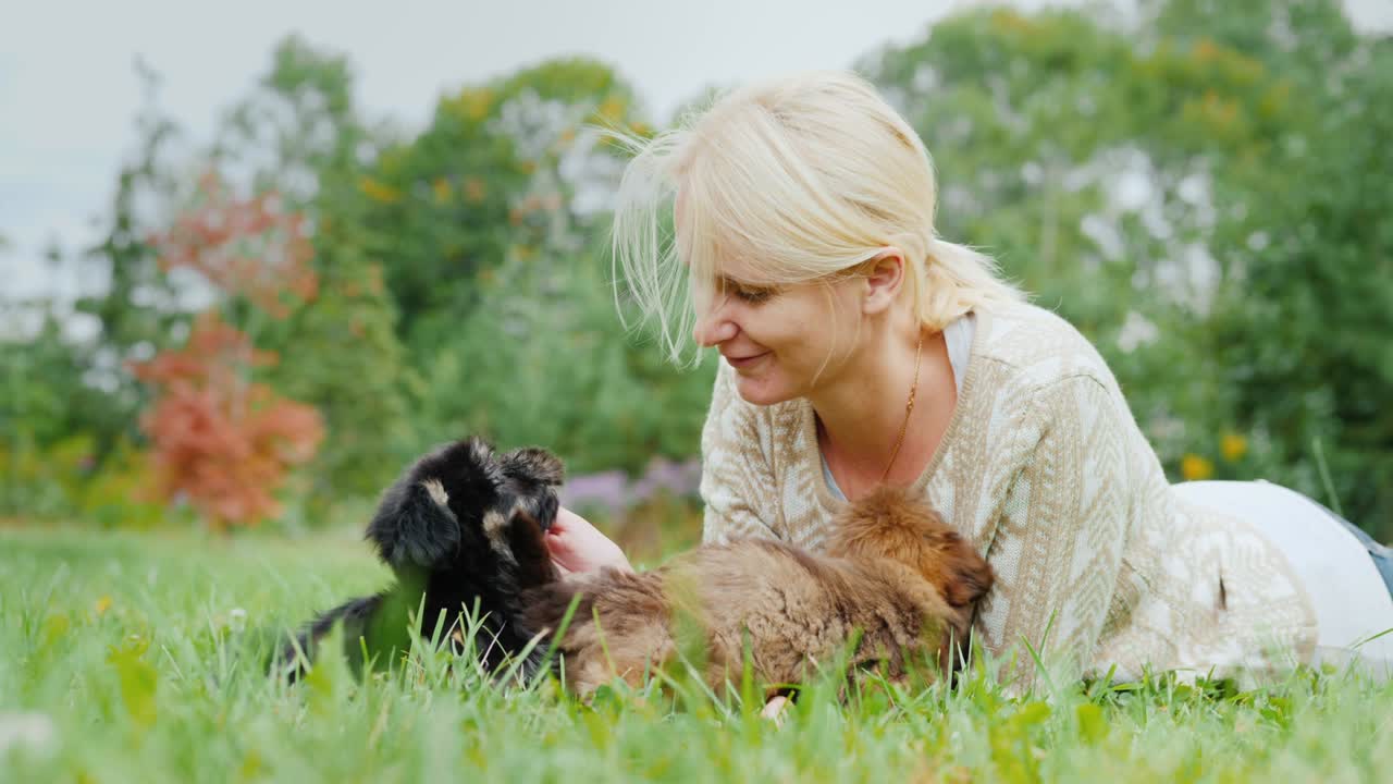 좋아하는 강아지와 함께 행복합니다. 한 여자가 두 개의 개와 함께 놀고, 그녀의 마당의 잔디에 누워 있습니다.
