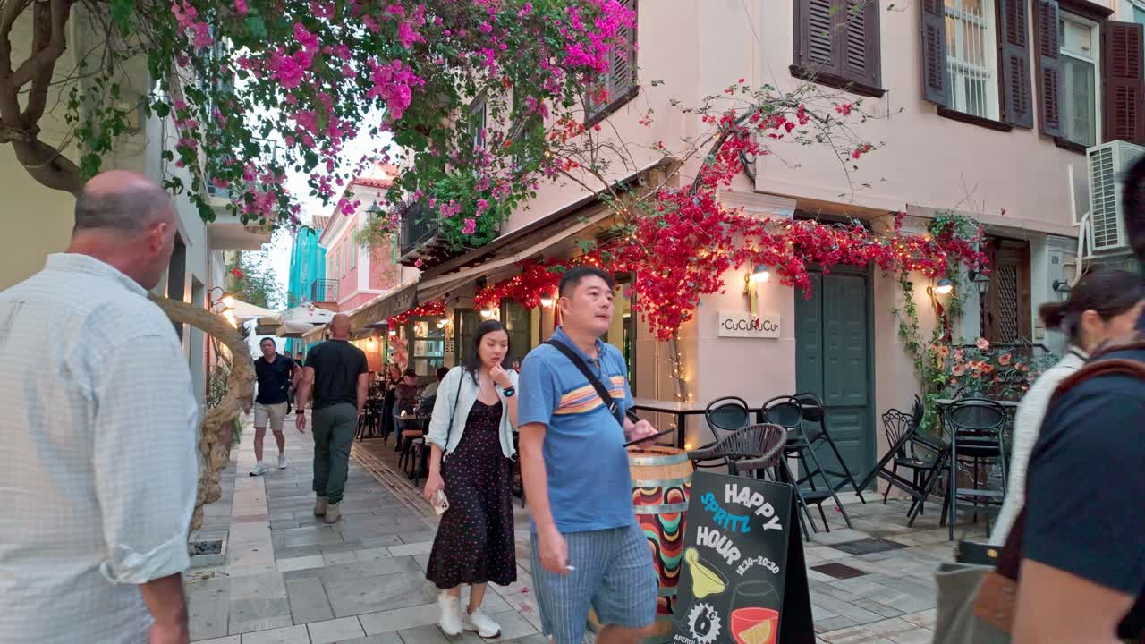 Asian tourists exploring narrow pretty streets Greek coastal city