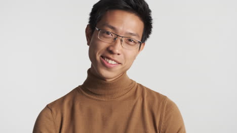안경을 쓴 아시아인 남자가 카메라를 쳐다보고 있다.
