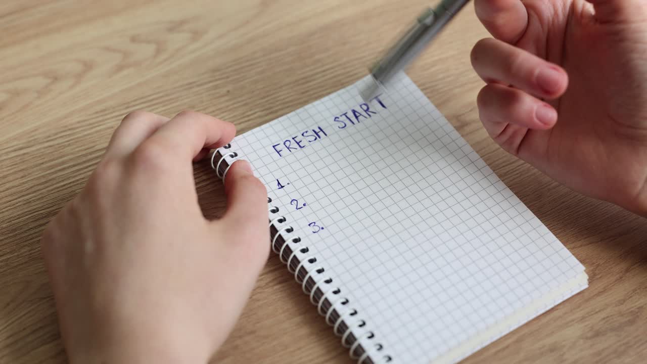 Hands writing "Fresh Start" in a notebook