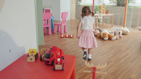 3-year-old little girl arrange her toys on a table after playing at indoor playground or playroom