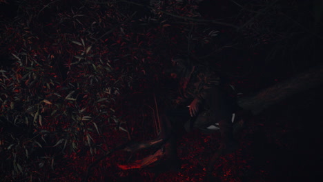 person sitting on a log in a dark forest at night
