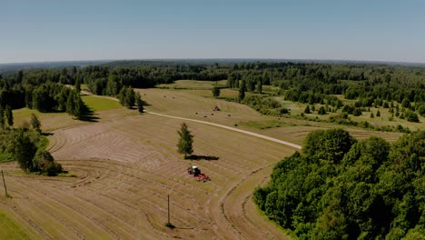 tractor collecting and baling hay rolls