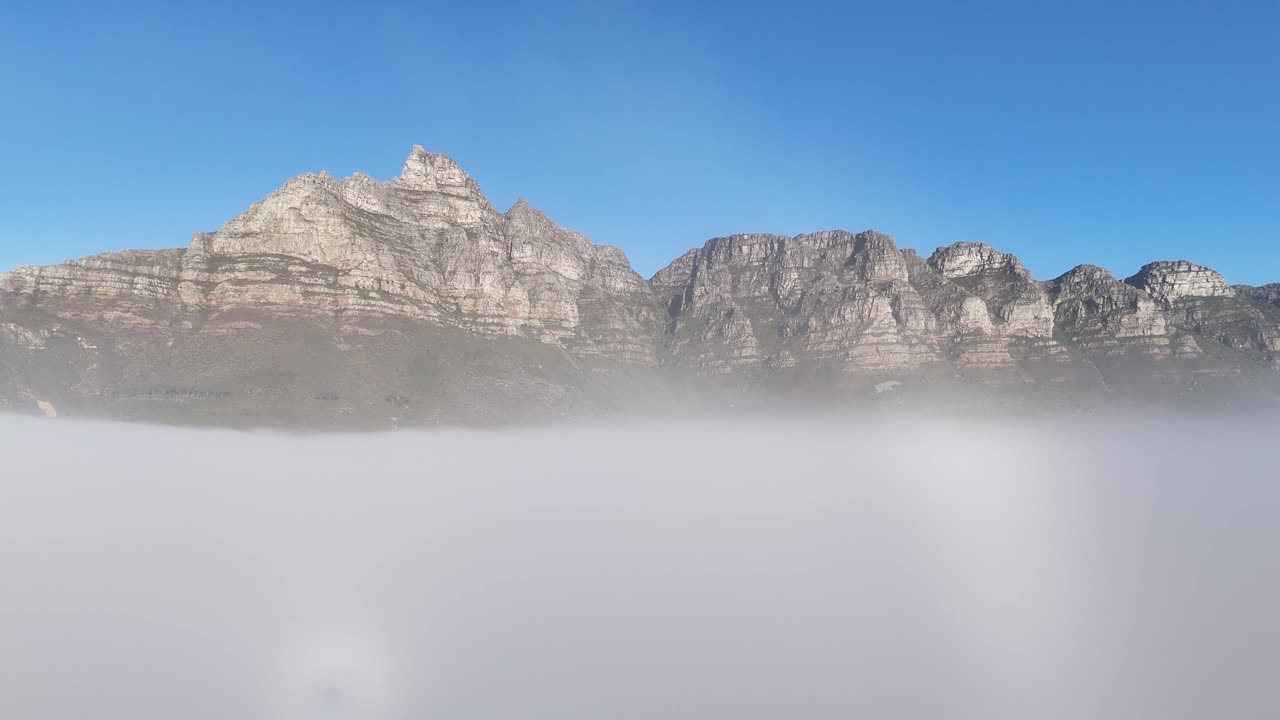 Aerial drone footage of table mountain in Cape Town, South Africa, surrounded by mist and clouds with only the peak emerging