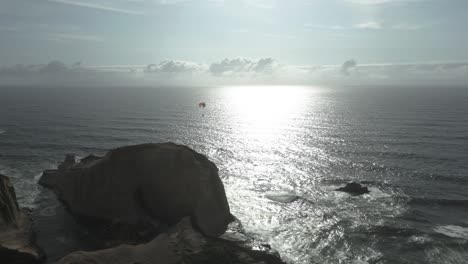 Flying-Paraglider-Over-Cape-Kiwanda-In-Pacific-City,-Oregon,-United-States-At-Sunset---Aerial-Drone-Shot