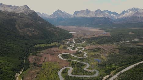 Vista-Aérea-De-Un-Valle-Con-Un-Río-Y-Montañas-Al-Fondo