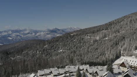 Eslovenia-Montañas-Pohorje-Con-Hotel-De-Esquí-Lukov-Dom-Y-Cabañas-Cubiertas-De-Nieve-A-La-Derecha,-Tiro-Aéreo-A-La-Izquierda