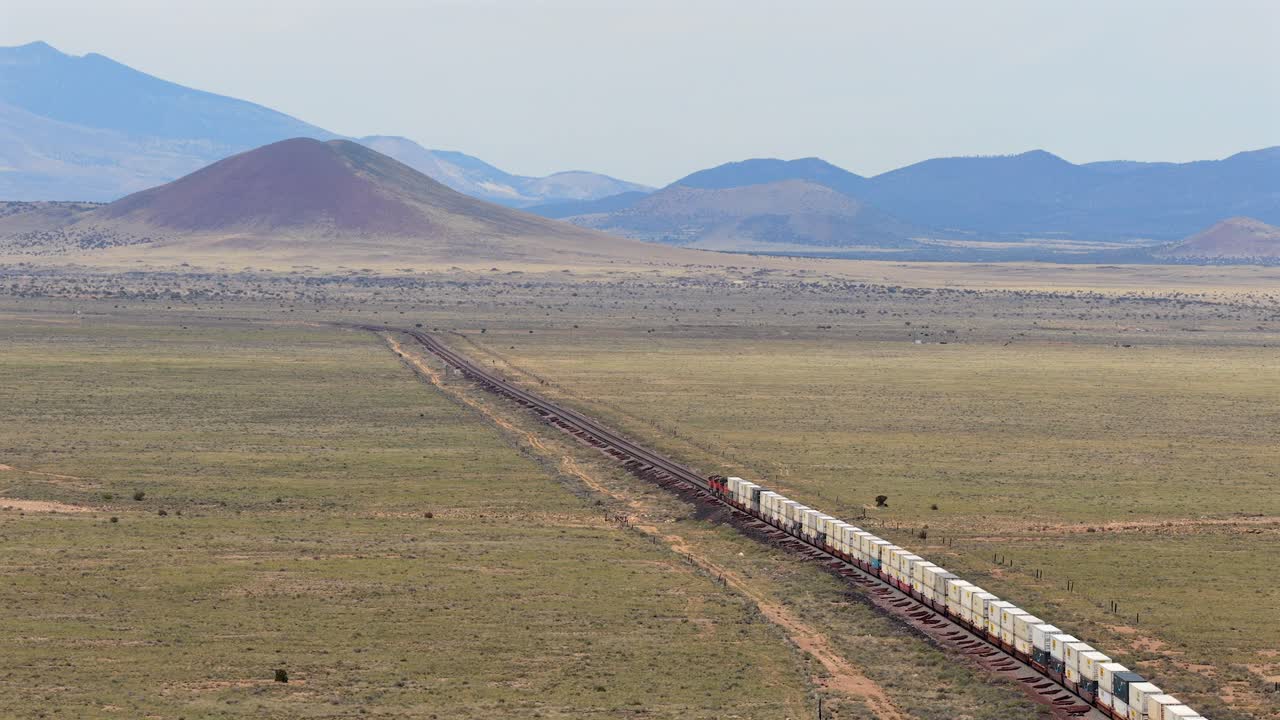 A drone following shot tracks a massive freight train as it navigates the vast southwest landscape, illustrating the intersection of industry and nature